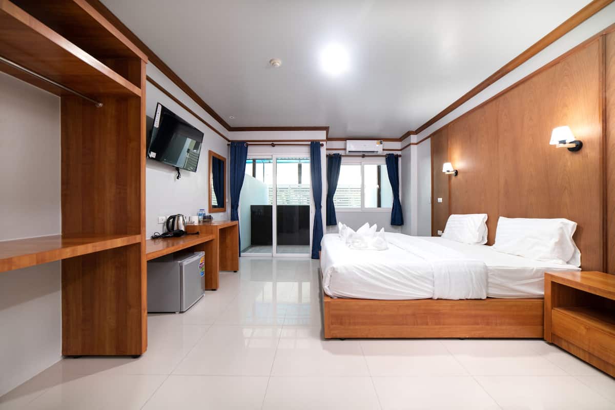 A modern hotel room with a wooden bed, a desk, and a television.