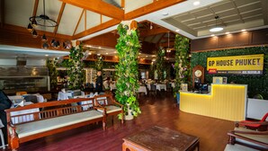 Een restaurantinterieur met houten banken, een receptiebalie en groene planten.