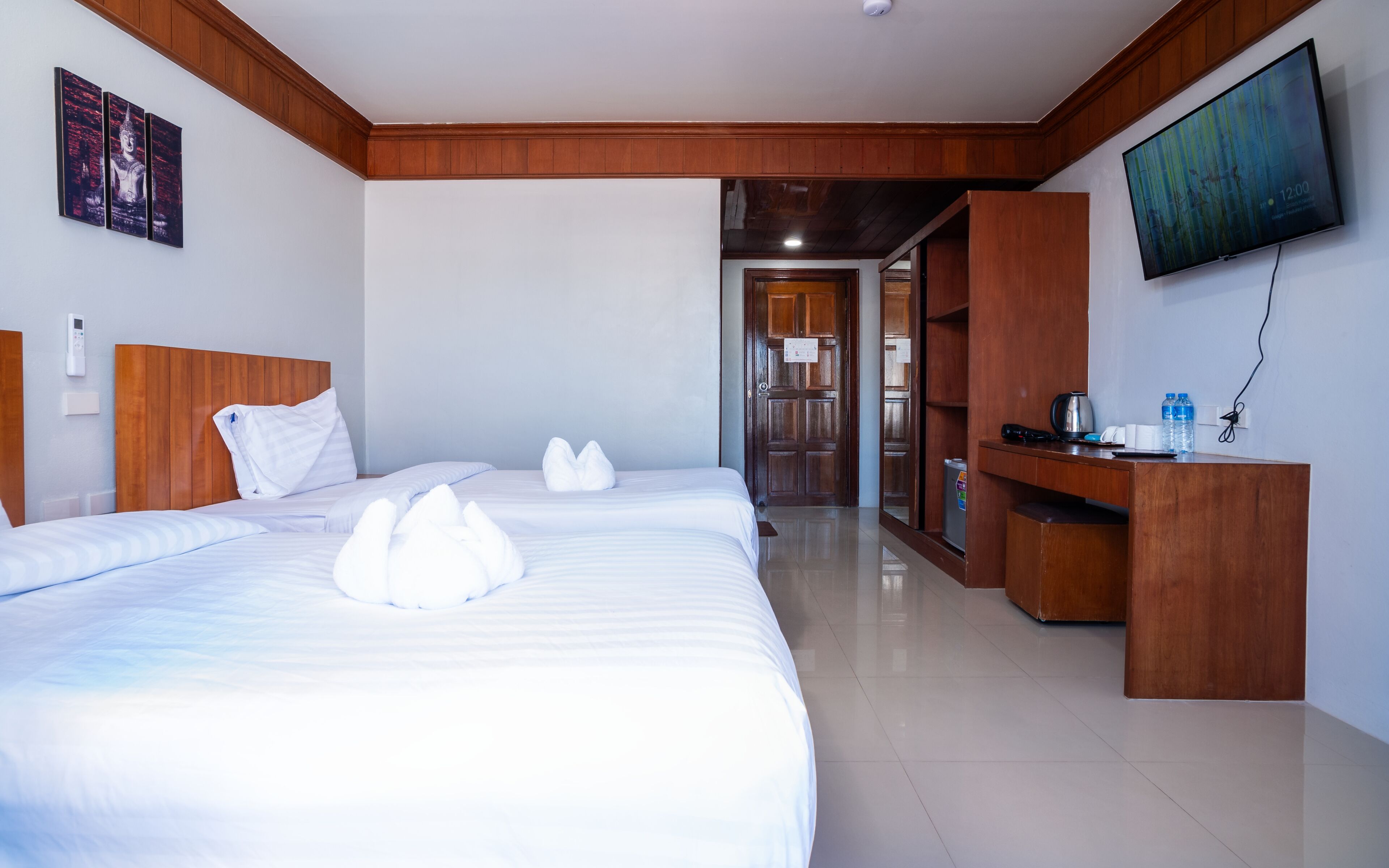 Habitación de hotel con una cama grande, cabecera de madera, televisor de pantalla plana, escritorio de madera y puerta que da a un pasillo.