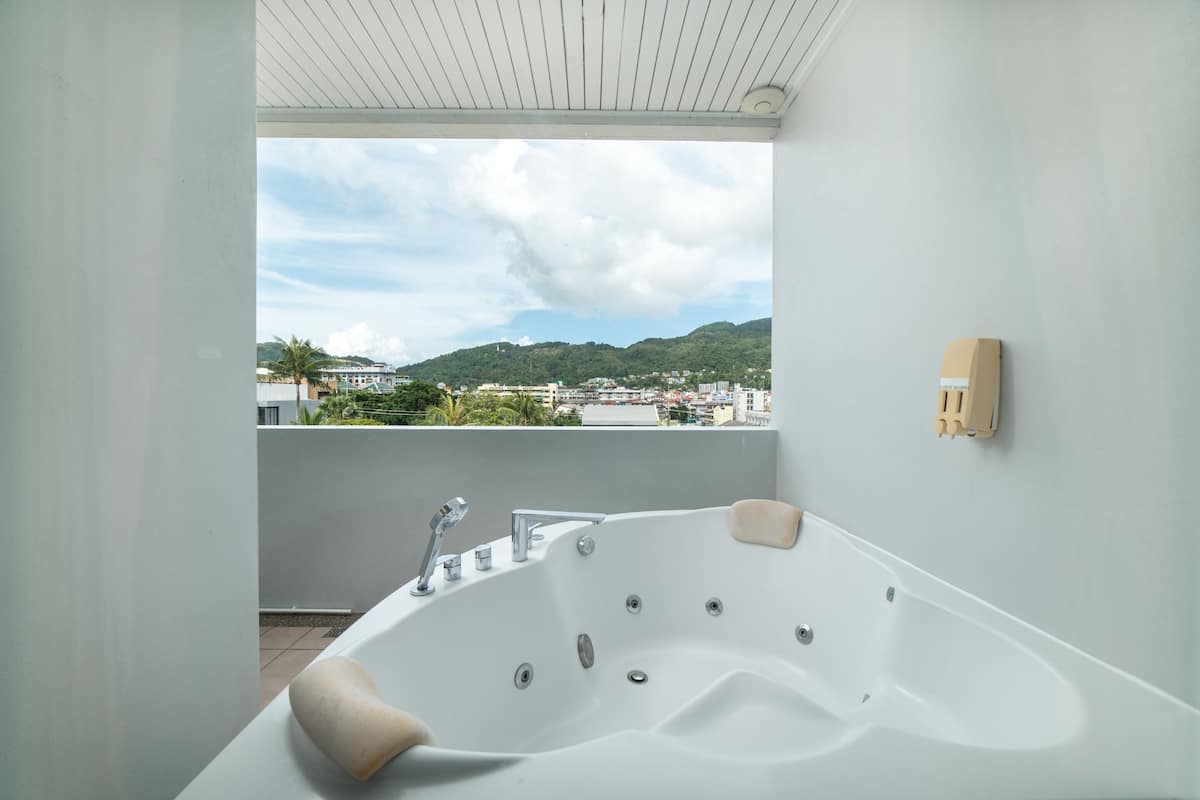 A modern bathroom with a large bathtub, a view of a cityscape, and a white ceiling.