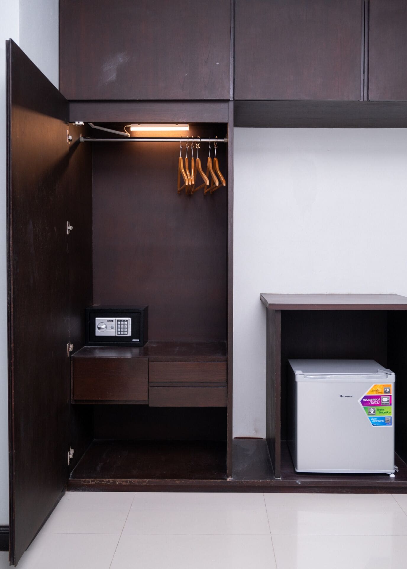 A walk-in closet with a built-in safe, a hanging rack, and a small refrigerator.