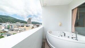 Een moderne badkamer met een groot bad, uitzicht op een stadsgezicht en een balkon met een hekwerk.