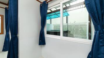 Una habitación con un ventanal grande, paredes blancas y cortinas azules.