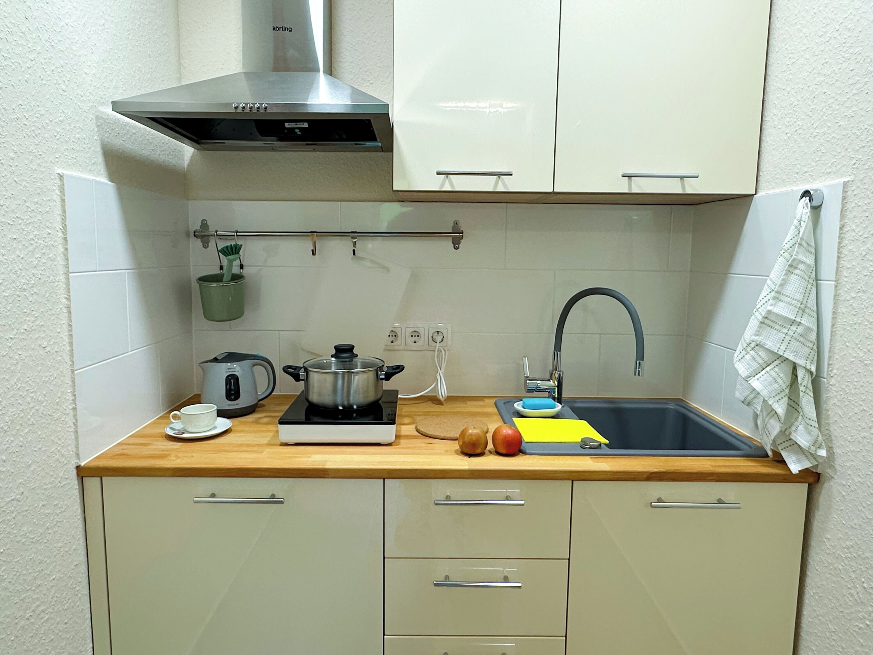 A compact kitchen with a stove, sink, and cabinets.