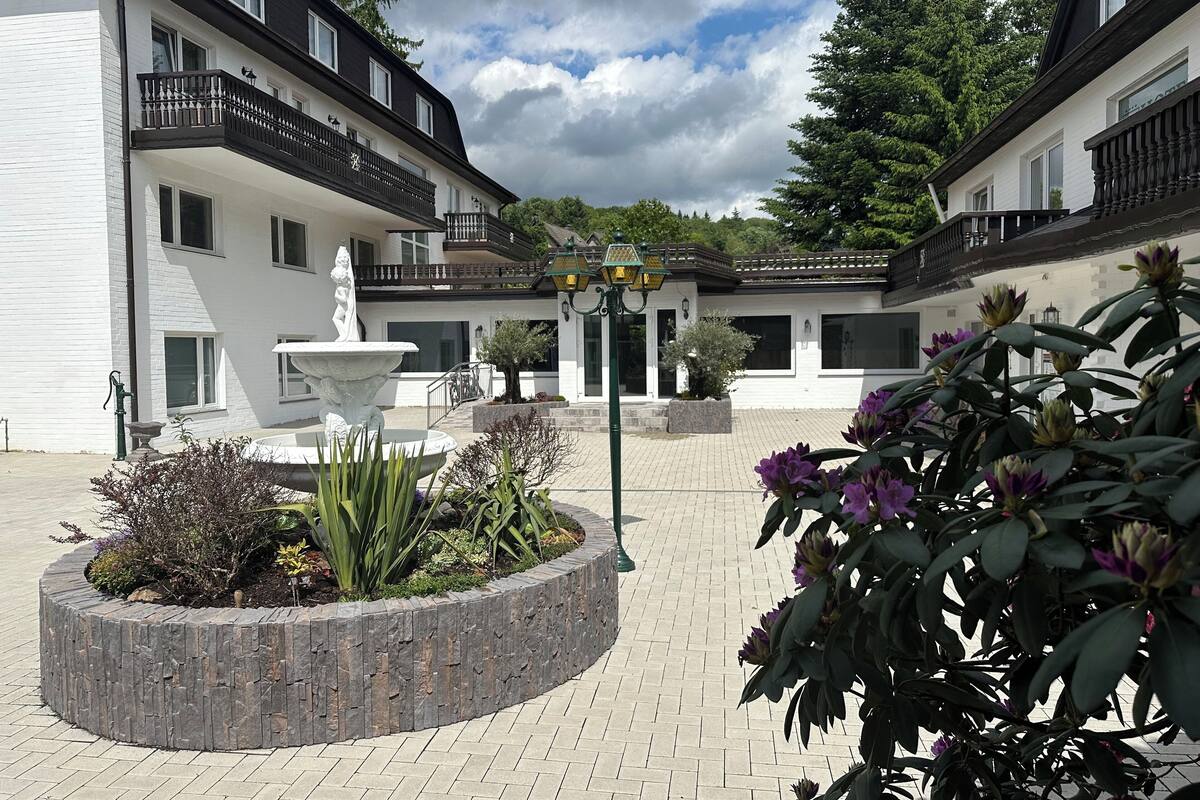Une cour avec une fontaine, des plantes en pot et un bâtiment doté de balcons.