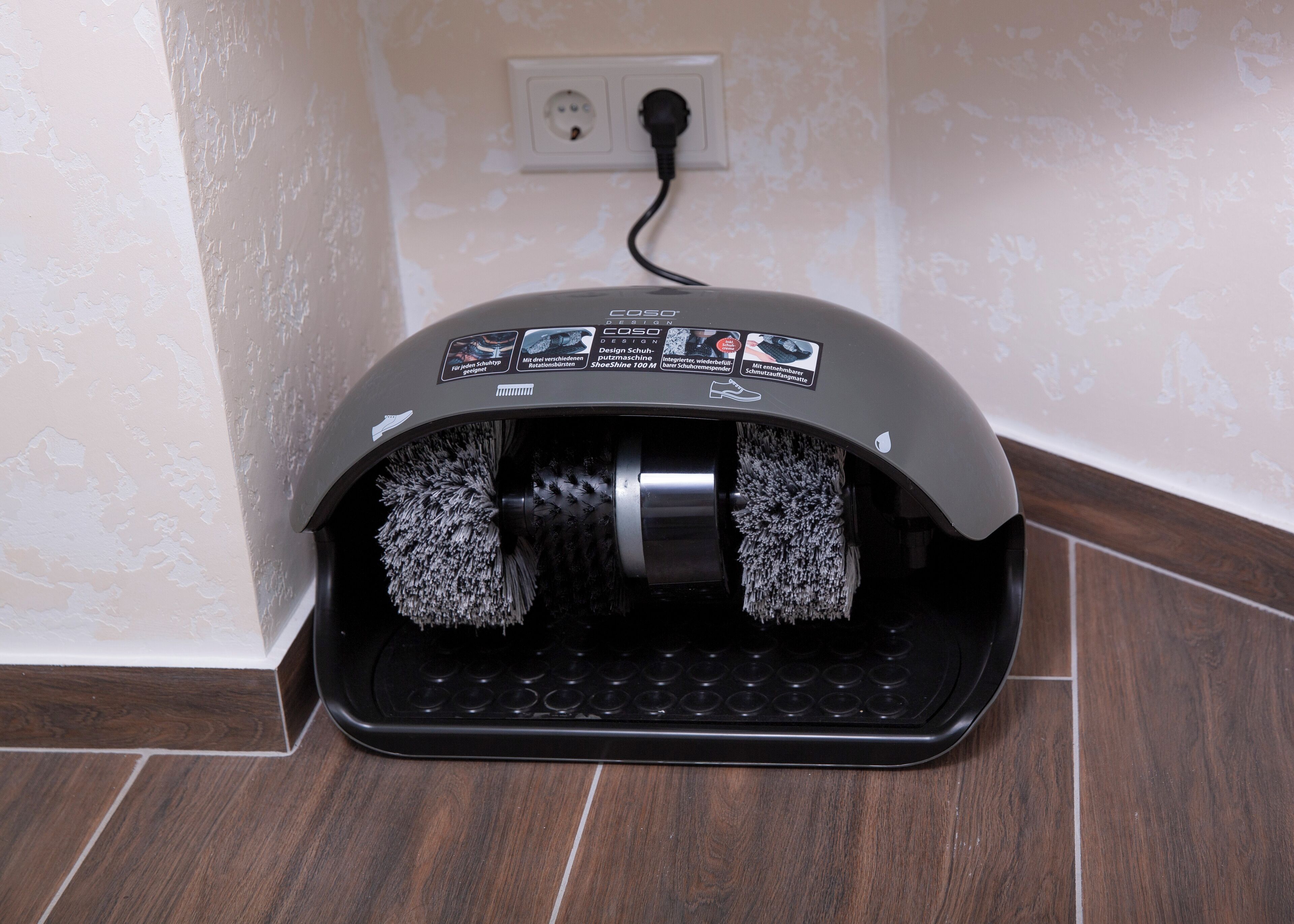 A shoe cleaning machine with a black base and grey top, featuring multiple brushes and a control panel.