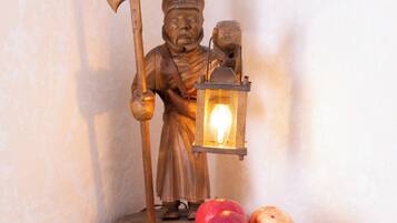 Una estatua de una figura sosteniendo un hacha y un farol, con un cuenco de manzanas al frente.