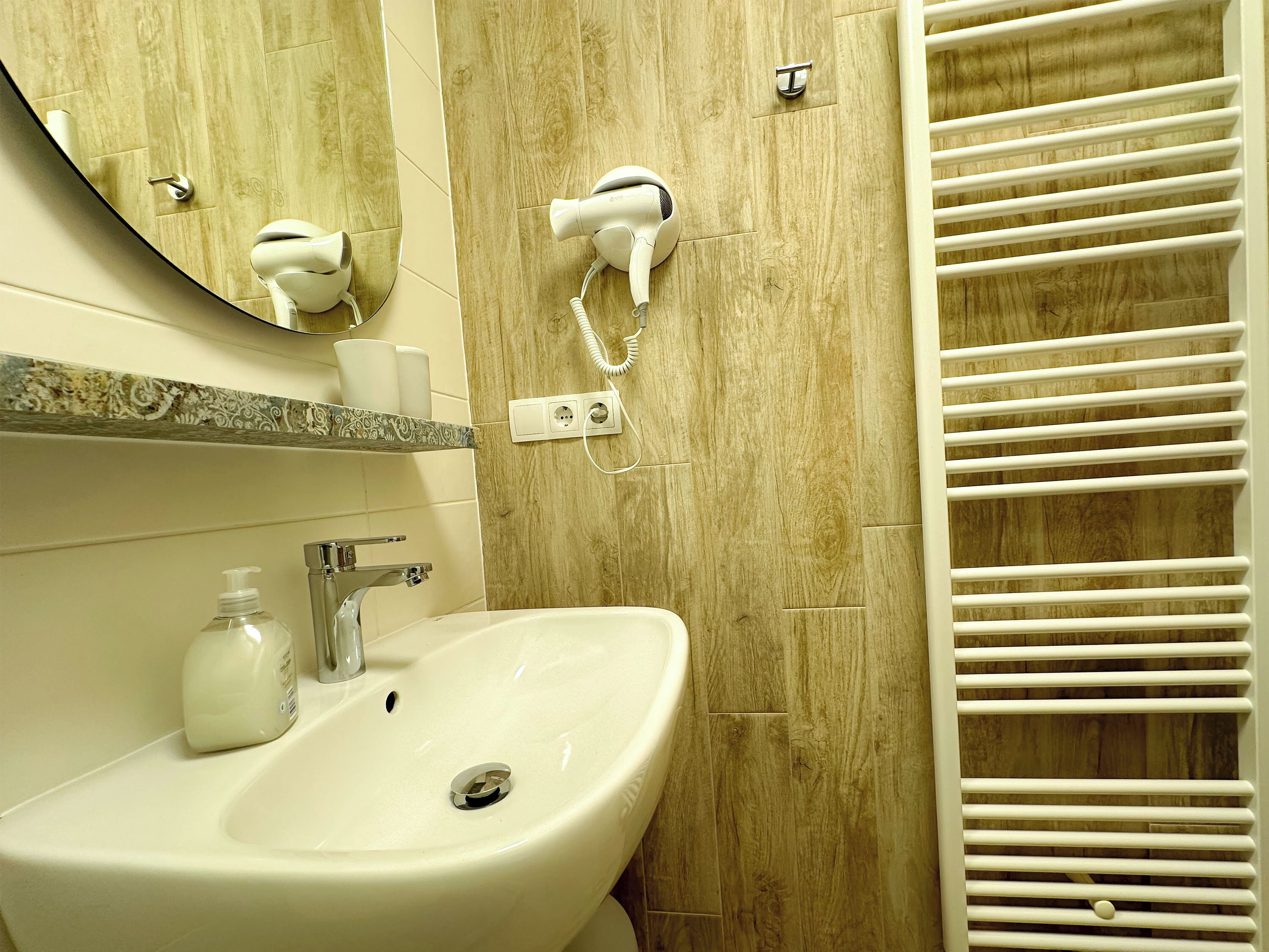 Un baño con lavamanos, espejo, secador de pelo y toallero.