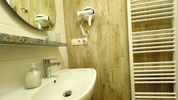 Un baño con lavamanos, espejo, secador de pelo y toallero.