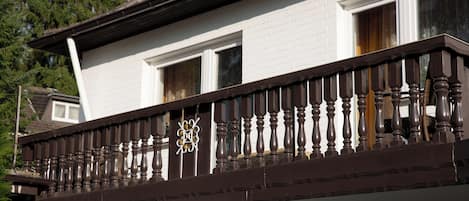 Een wit gebouw met een balkon, voorzien van donkerhouten spijlen en een decoratieve top.