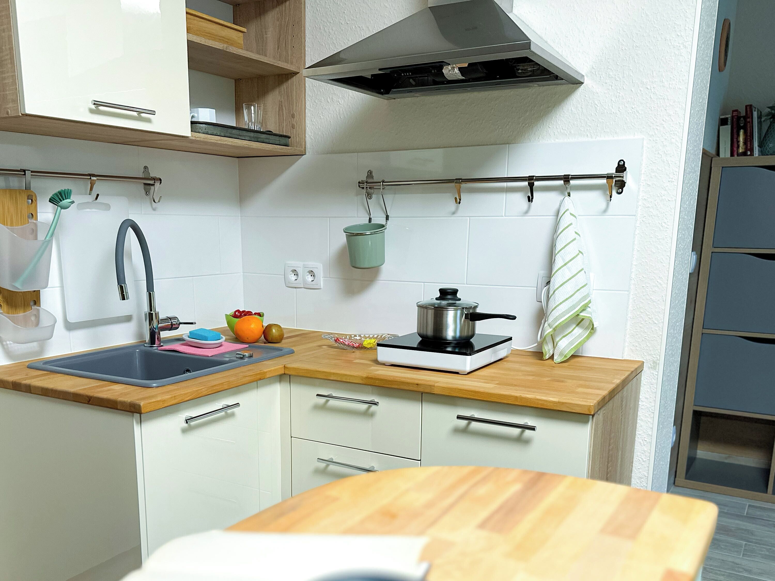A modern kitchen with a sink, countertop, and a portable stove.