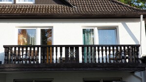 A two-story house with a tiled roof, white exterior walls, and a balcony with a wrought iron railing. - Hotel Waldberg (Stolberg)