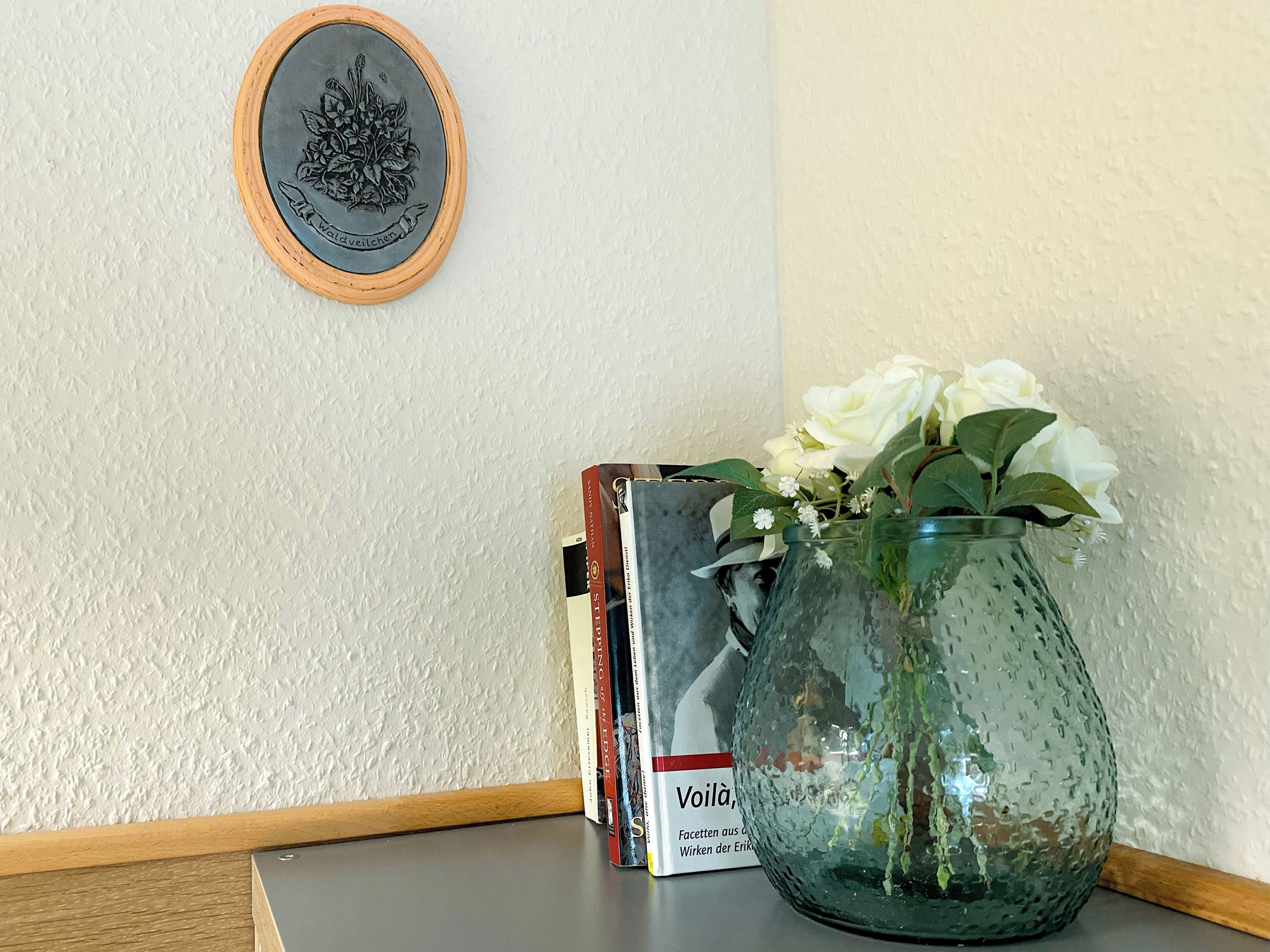 Ein Bücherregal mit Büchern und einer Vase mit weißen Blumen.