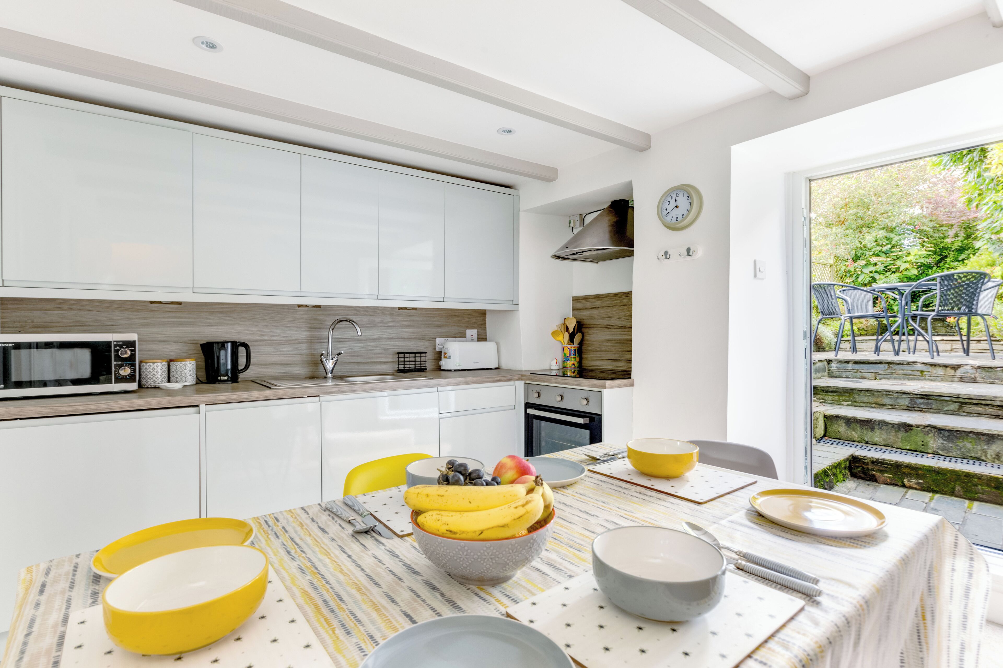 A modern kitchen with white cabinets, a microwave, and a dining area with a table set for two.