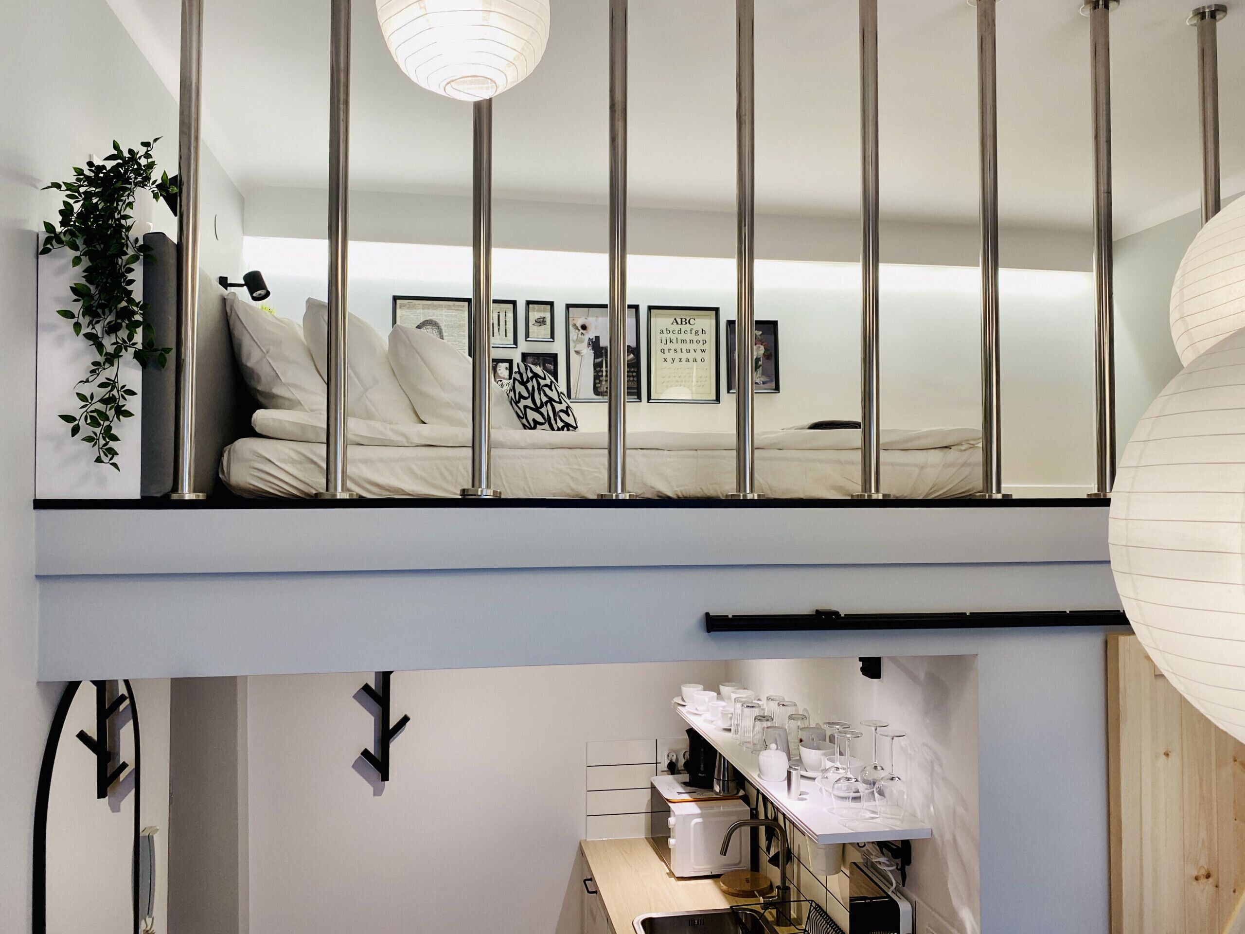 Une chambre de style loft moderne avec balcon, un espace cuisine en contrebas et une table à manger dressée avec des verres.