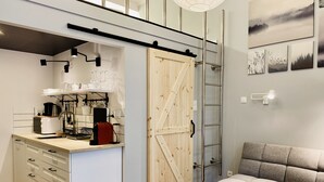 Et kompakt køkken med en trædør, en indbygget bænk og et spiseområde med en sofa.