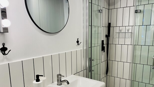 A bathroom with a white sink, mirror, and glass shower enclosure. - Sebastiana 22/7 (Kraków)