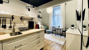 Et moderne køkken med hvide skabe, en integreret vask og et spiseområde med bord og stole.