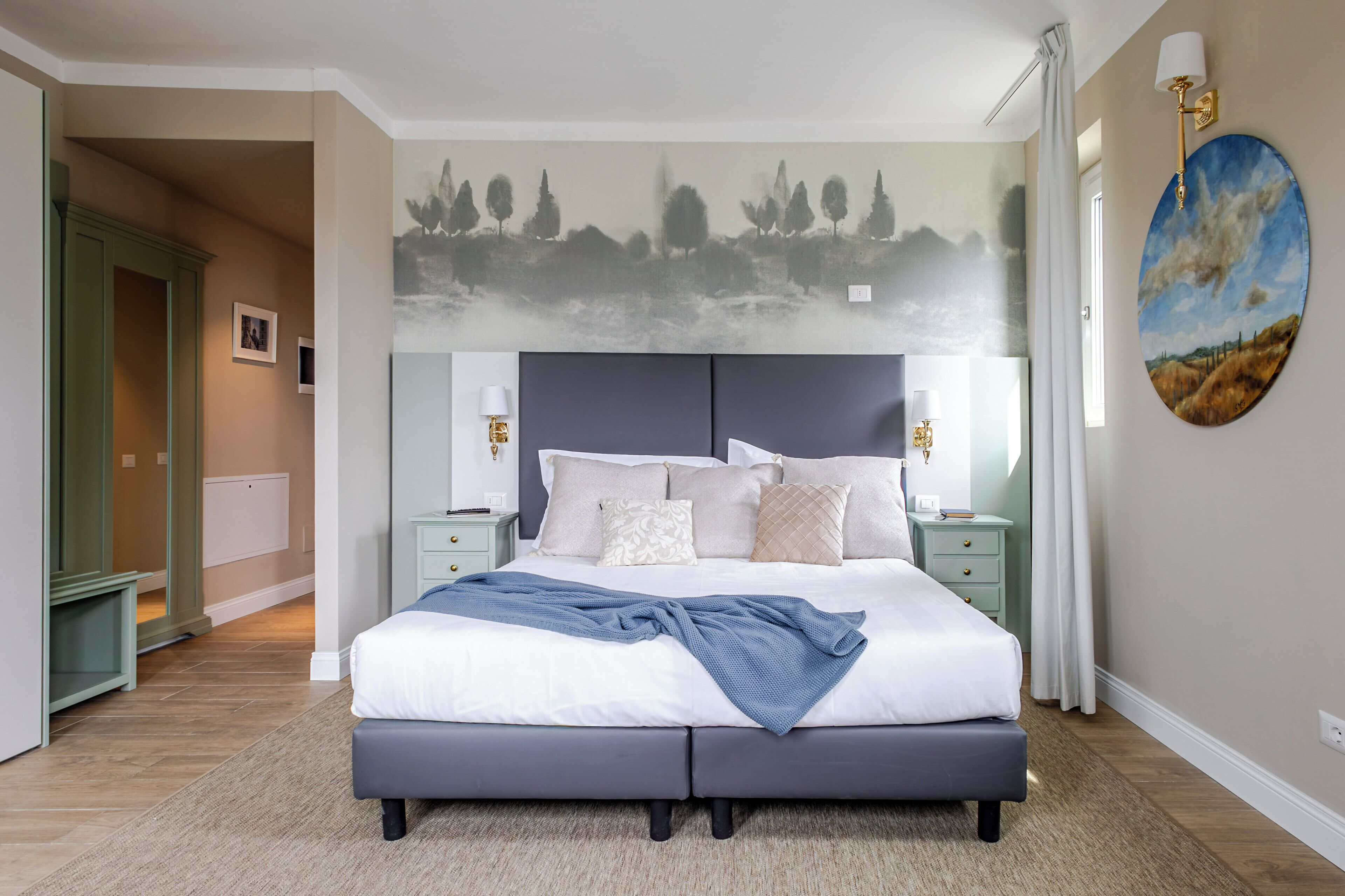 Una camera da letto con un letto grande, comodini, una lampada a parete e un quadro.