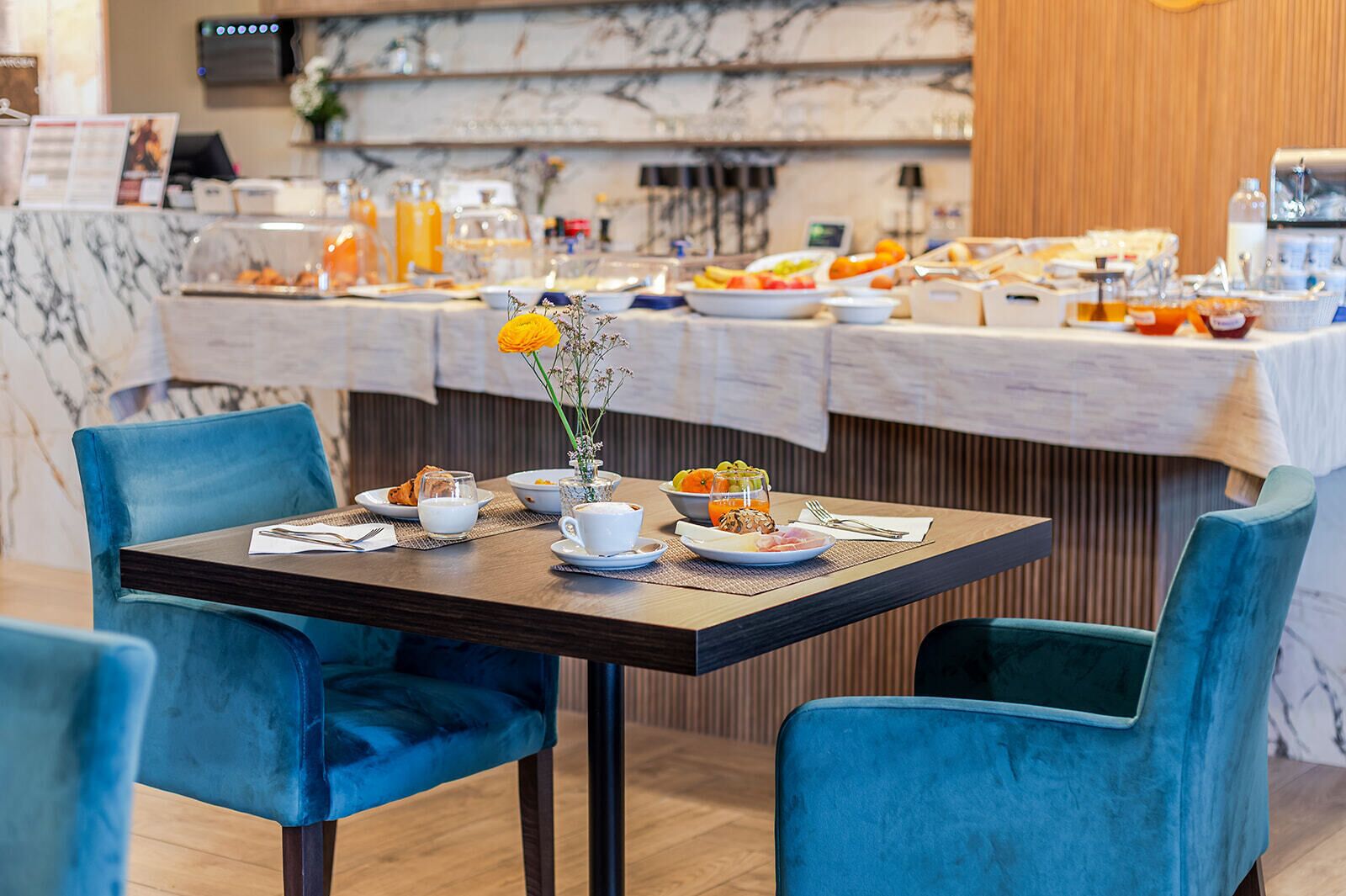 A breakfast buffet with various food items and a vase with flowers on a table.