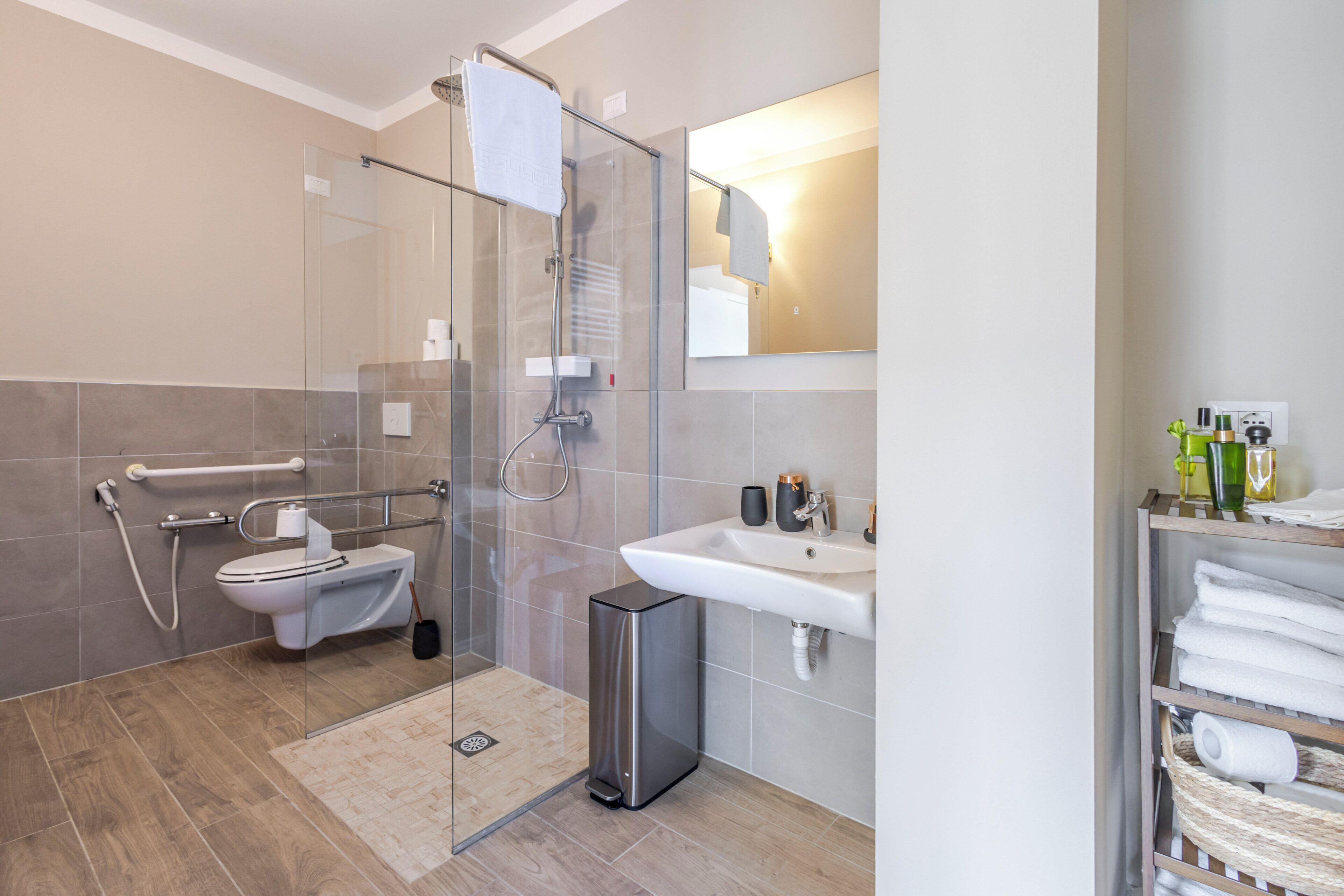Ein modernes Badezimmer mit Duschkabine aus Glas, Toilette, Waschbecken und Spiegel.