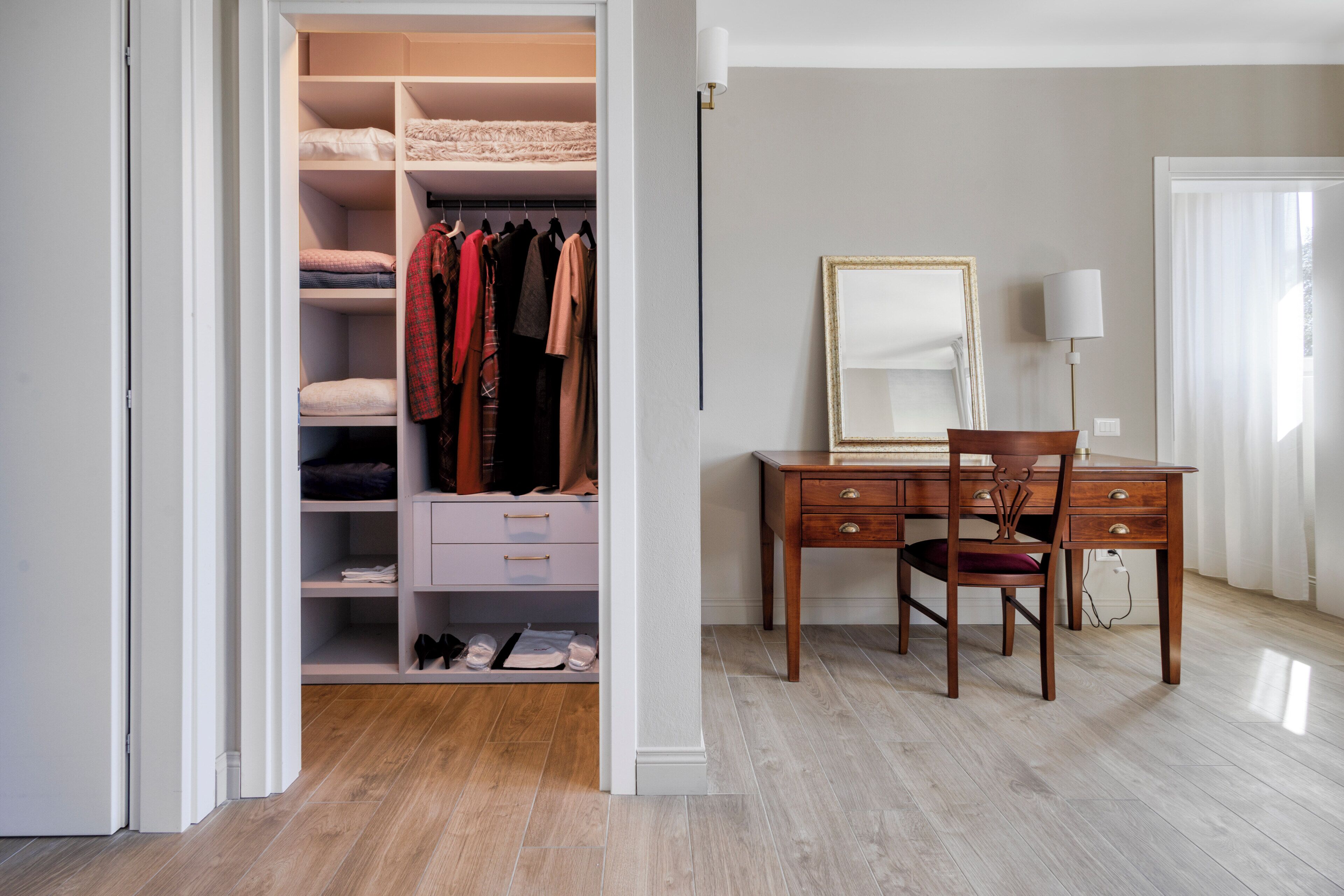 Une chambre à coucher avec un bureau en bois, une chaise, une armoire et un miroir.