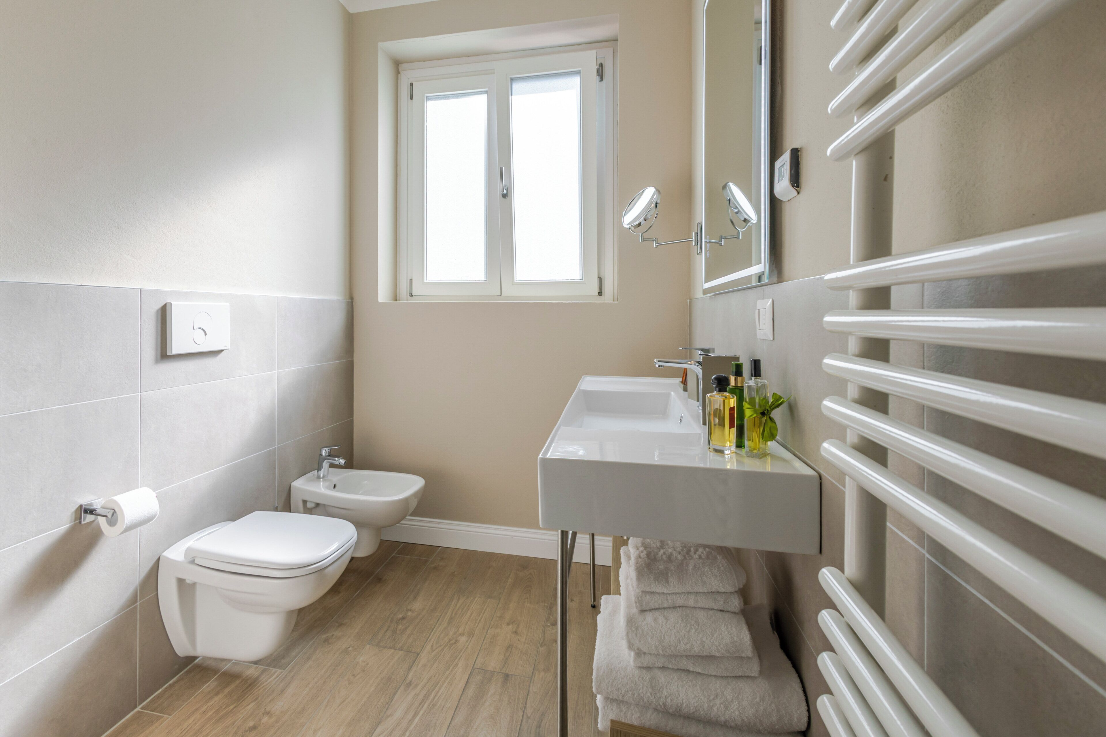A modern bathroom with a toilet, bidet, sink, and towel rack.