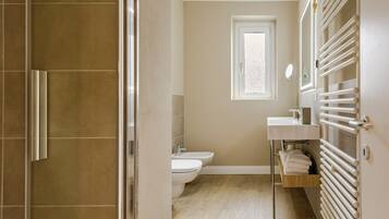 Een badkamer met douche, toilet, wastafel en handdoekrek.