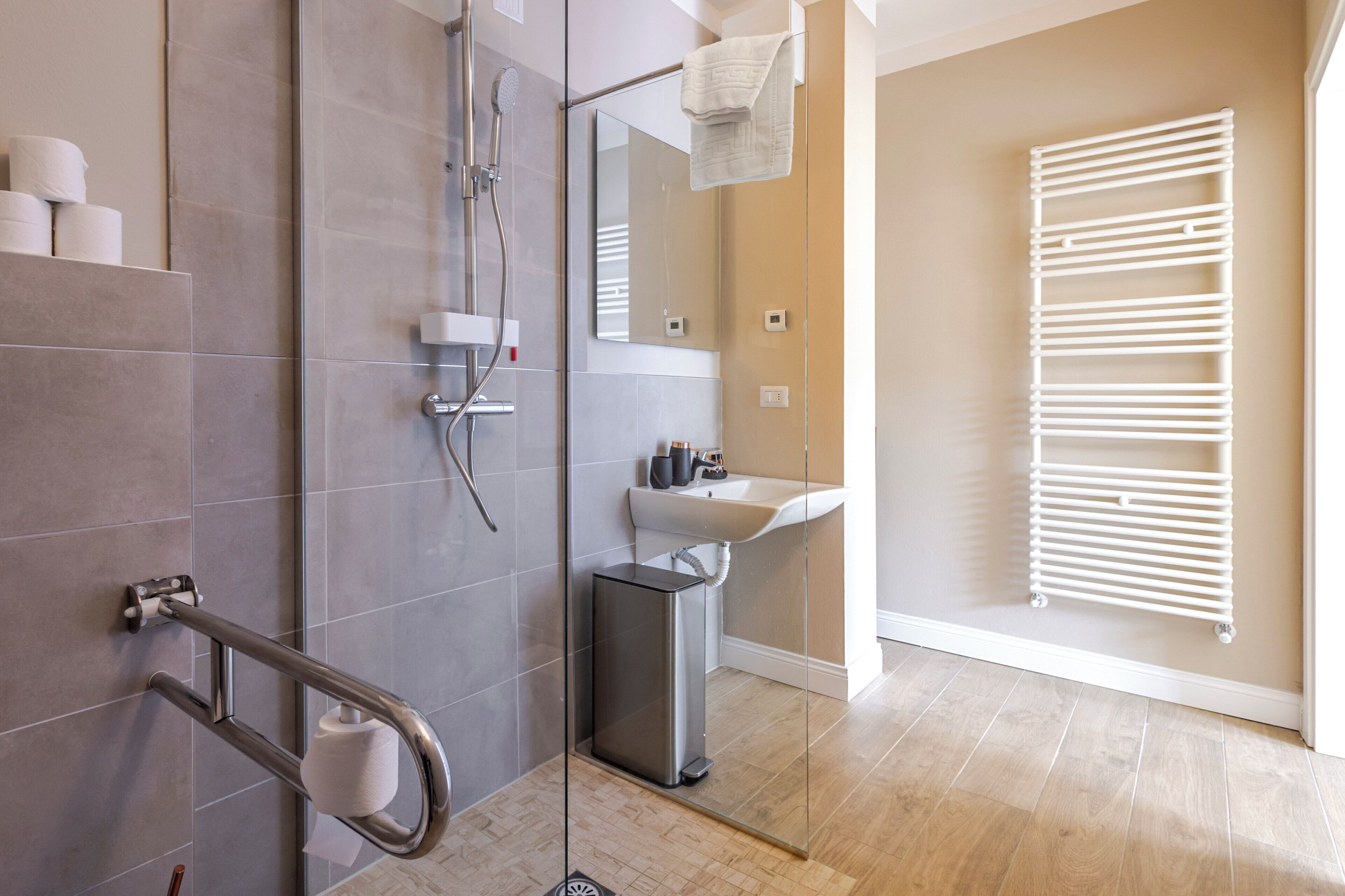 Un bagno moderno con box doccia in vetro, lavandino bianco e porta asciugamani.