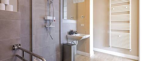 Un bagno moderno con box doccia in vetro, lavandino bianco e porta asciugamani.