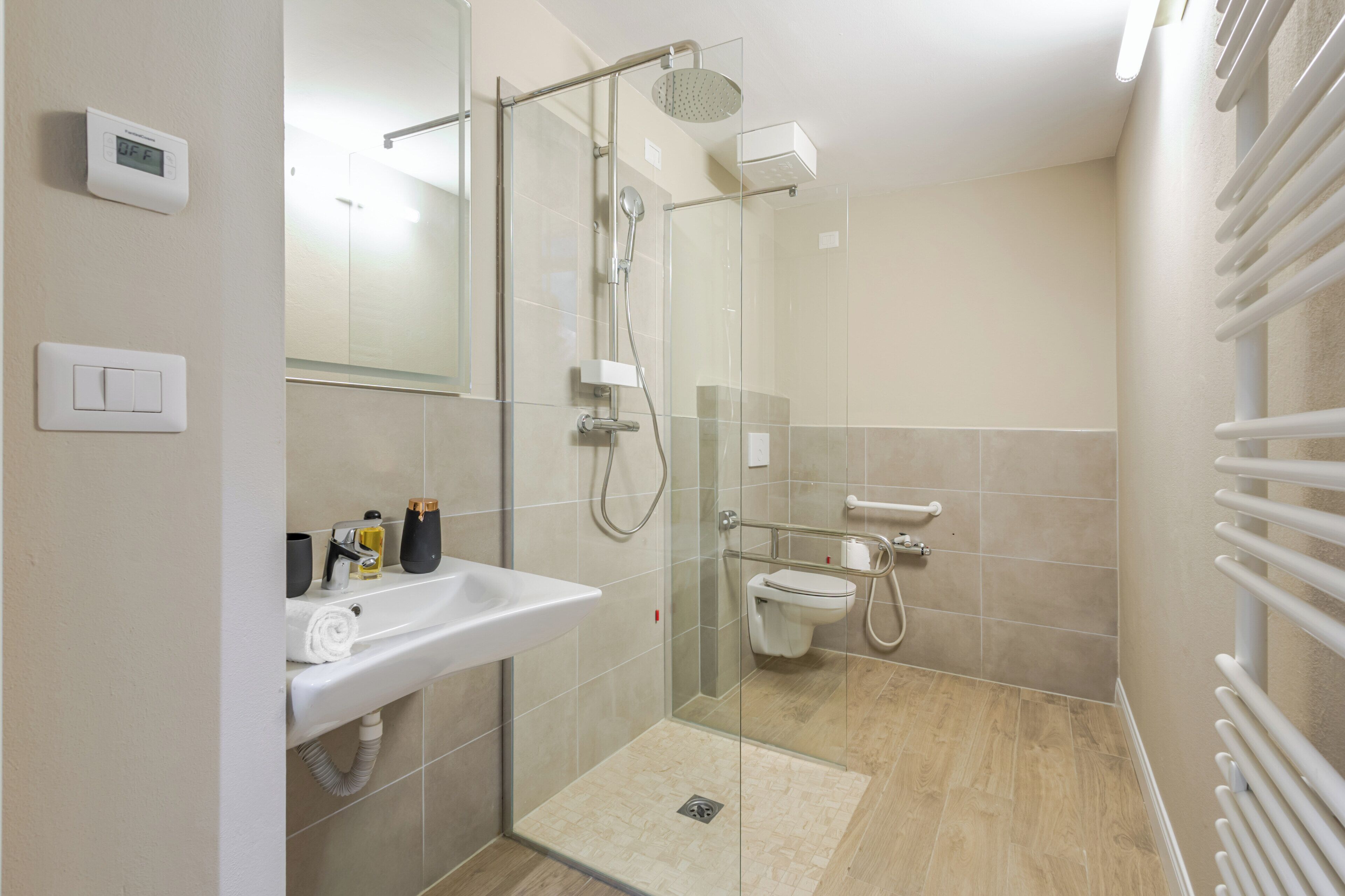 A modern bathroom with a glass-enclosed shower, a white sink, and a toilet.