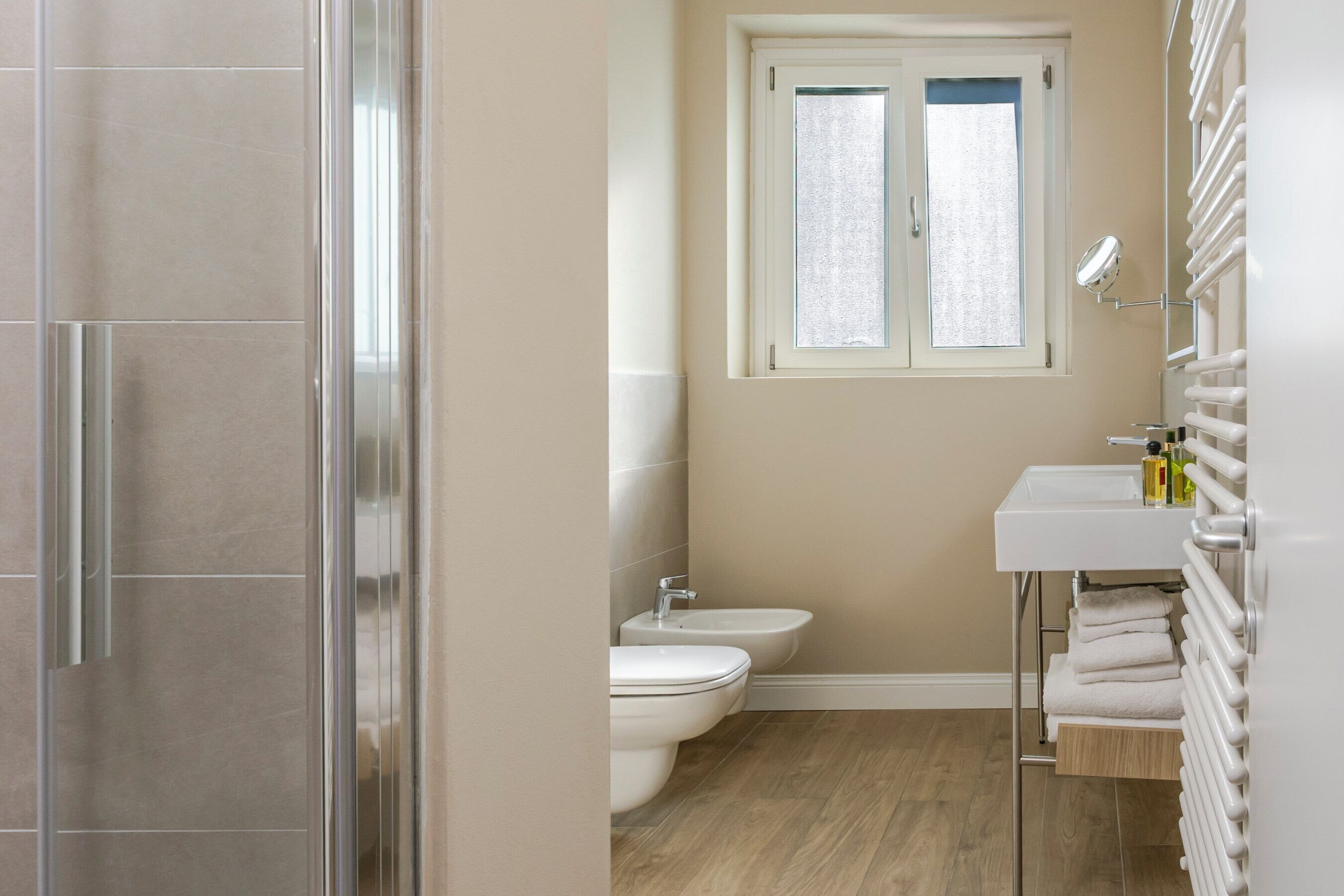 A bathroom with a toilet, bidet, and a window.
