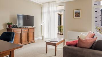 A living room with a TV, wooden cabinet, and a sofa with cushions.