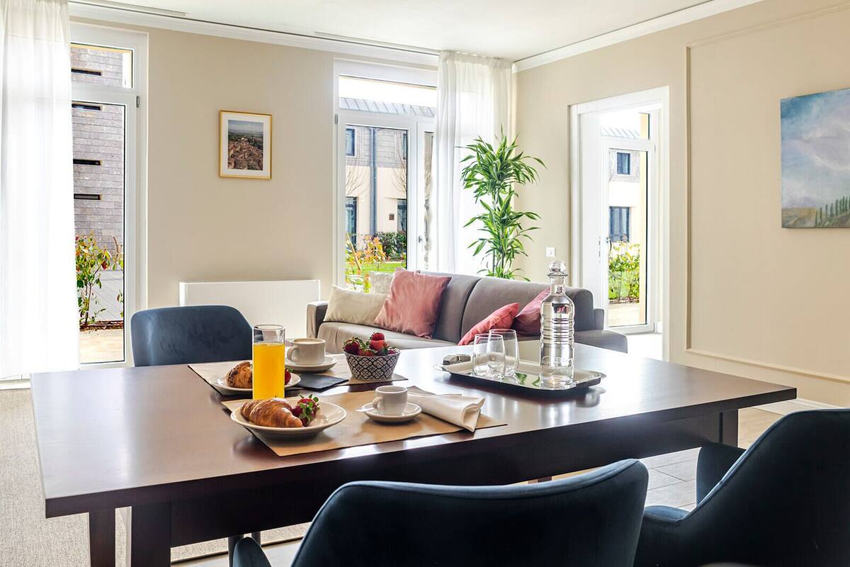 Un coin repas avec une table mise pour le petit-déjeuner, un canapé et une plante en pot.
