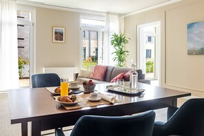 Un coin repas avec une table mise pour le petit-déjeuner, un canapé et une plante en pot.
