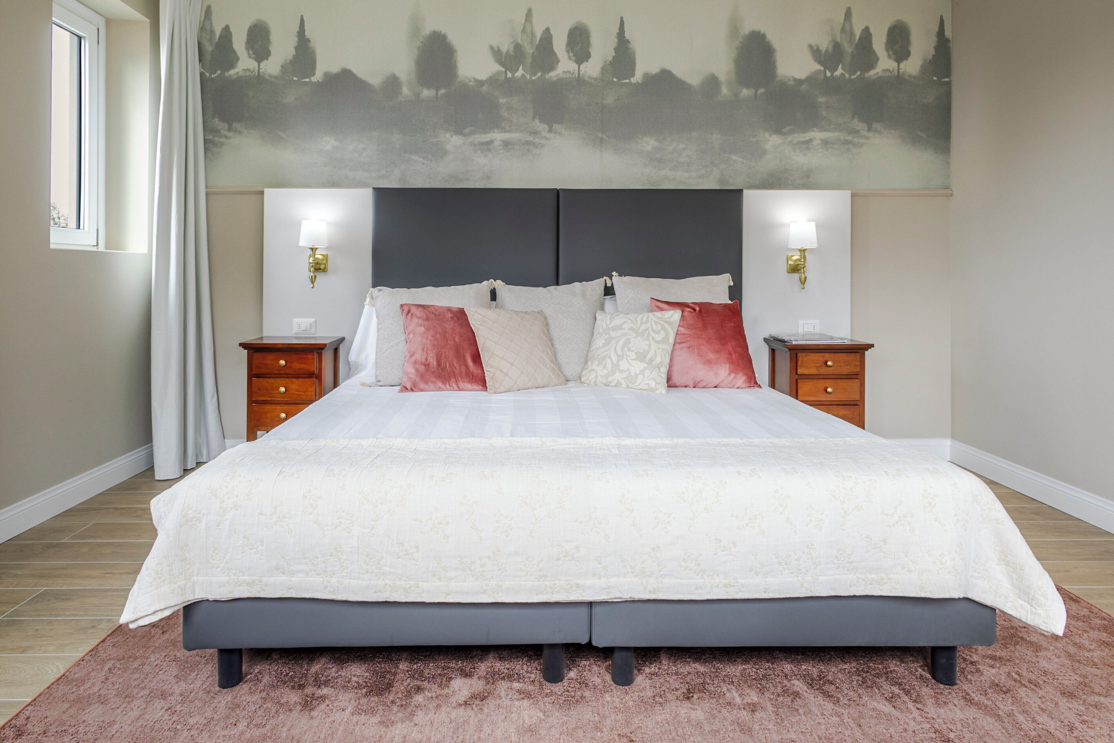 Een slaapkamer met een groot bed, twee nachtkastjes, een hoofdbord en een wandlamp.