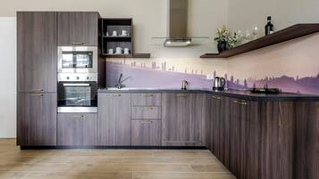 A modern kitchen with dark wood cabinetry, a built-in oven, and a stainless steel range hood.