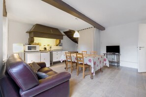Un espace de vie compact comprenant un canapé, une table à manger, un coin cuisine et un téléviseur.