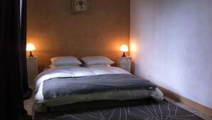 Een eenpersoonsbed met twee nachtkastjes, elk met een lamp, in een kamer met effen muren en een eenvoudig design.