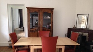 A dining room with a wooden table and red chairs, a wooden cabinet with glass doors, and a fireplace. - Location au pied du vercors (Vinay)