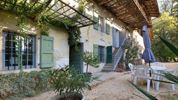 Un bâtiment doté d’un patio couvert, d’un espace extérieur aménagé pour s’asseoir et d’un escalier menant à l’entrée.