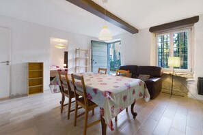 A dining area with a table set for four, a sofa, and a window with a view of greenery.