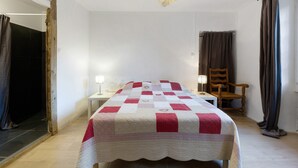 Une chambre à coucher comprenant un lit, une table de chevet, une chaise, un bureau et un luminaire suspendu.