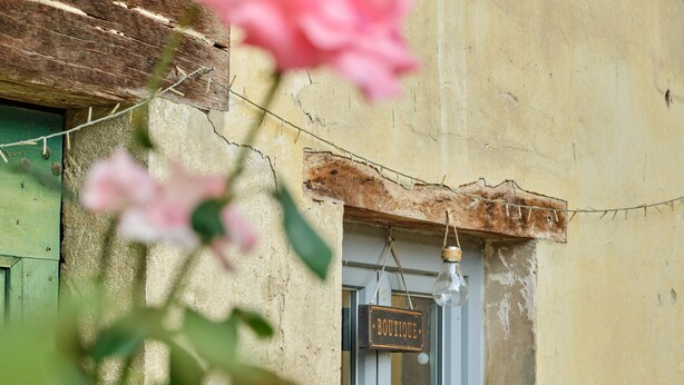 Un edificio rústico con un letrero que dice 'BOUTIQUE', una puerta de madera y una ventana.