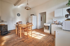 Una cocina con piso de madera, una mesa de comedor con sillas, un refrigerador, un horno y un microondas.