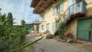 Un edificio con un patio de grava, asientos al aire libre y una escalera que conduce a una puerta verde.
