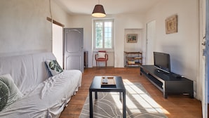 Una sala de estar con sofá, mesa de centro, mueble para televisión y ventana.