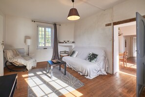 Una habitación con sofá, mesa, lámpara, silla y ventana.