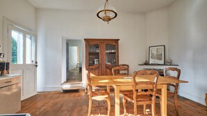 Un comedor con una mesa y sillas de madera, un aparador y una araña.