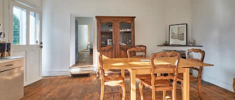 A dining room with a wooden table and chairs, a cabinet, and a chandelier.